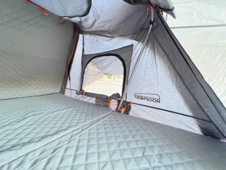 Inside a Roofnest roof-top tent, with quilted bedding & open window views. Ideal for your next rv rental adventure.. Ady ORT 2022