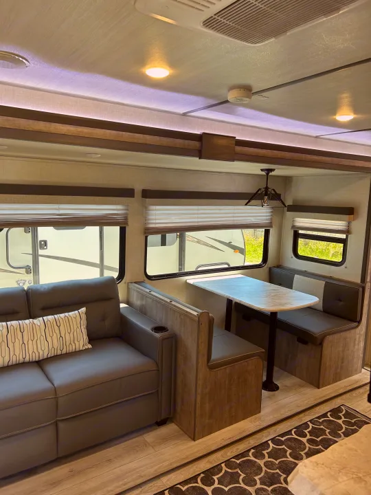 Cozy RV rental interior: sofa, dinette, modern decor for a comfortable travel experience.. Forest River Surveyor 2023