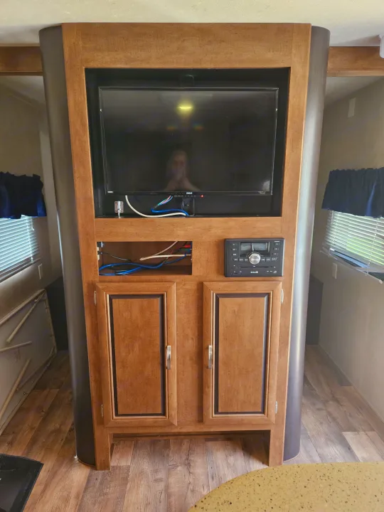 RV rental living space with a built-in wood entertainment center, TV, and stereo system, showing functional cabin features.. Forest River Salem 2017