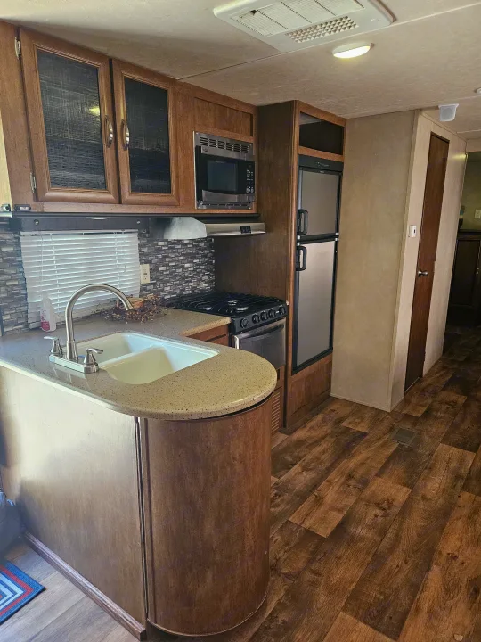 Modern RV rental kitchen with wood cabinets, full appliances, and stone-look counters.. Forest River Salem 2017