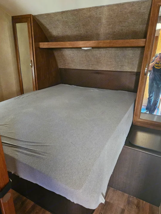 Compact RV rental bedroom featuring a bed with overhead shelf, side cabinets, and ample built-in storage.. Forest River Salem 2017