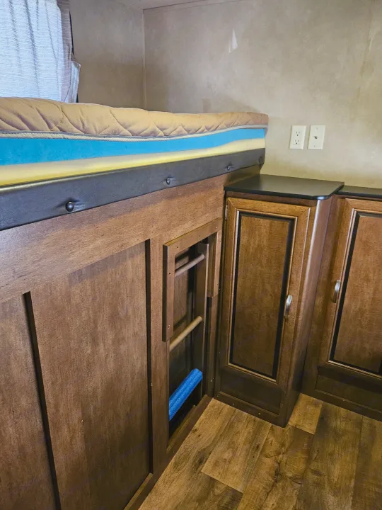 Compact RV rental interior: bunk bed with layered mattress, pull-out ladder, wood cabinets, and wall outlets.. Forest River Salem 2017