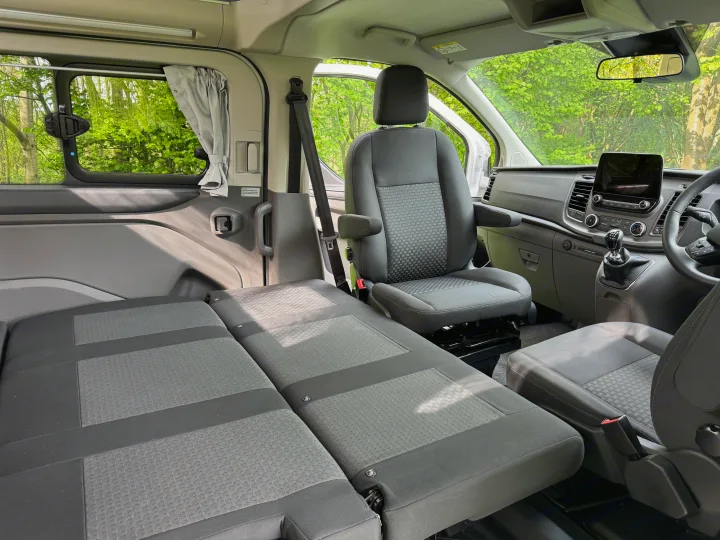RV rental camper van interior: rear seats convert to a bed, front seat swivels for flexible living and sleeping.. Ford Nugget 2022