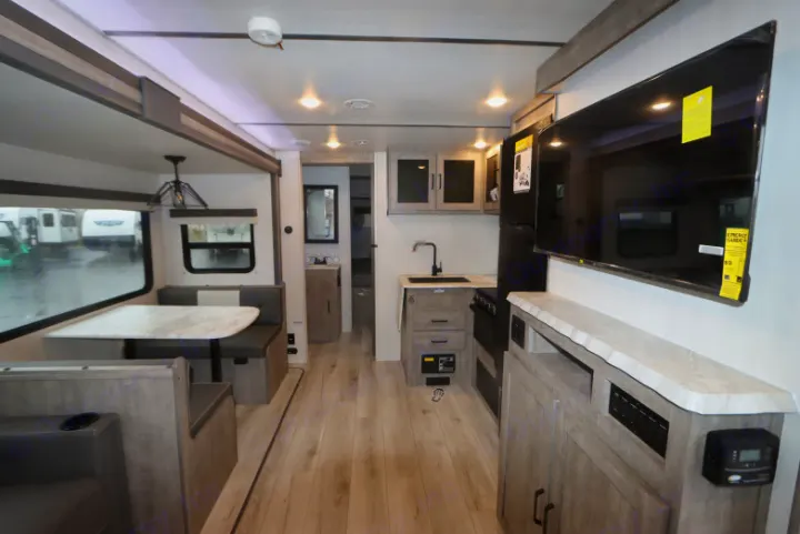 Spacious RV rental interior features a modern kitchen, dinette, and entertainment center with a large TV.. Forest River surveyor Legand 2023