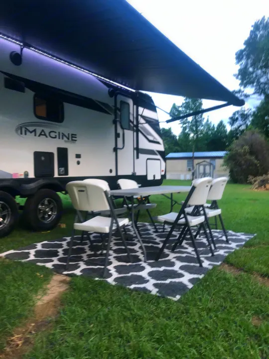 Enjoy this RV rental's inviting outdoor space, complete with an extended awning, LED lights, table, chairs, and a stylish rug.. Grand Design Imagine 2023