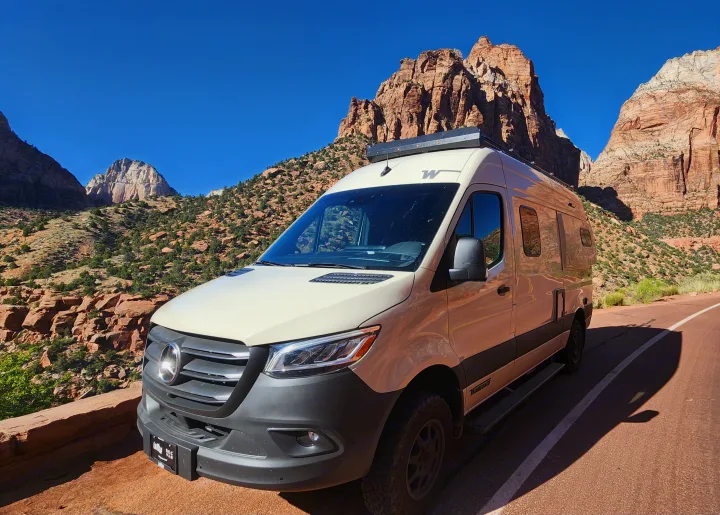 RV rental Winnebago camper van on a scenic road in Zion National Park, showcasing stunning red rock scenery.. Winnebago Revel 2024