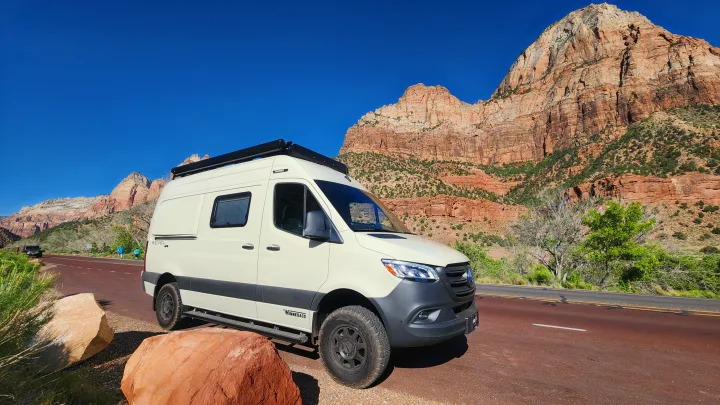 Cream Winnebago Revel rv rental parked by red rock mountains. Perfect for a national park road trip adventure.. Winnebago Revel 2024