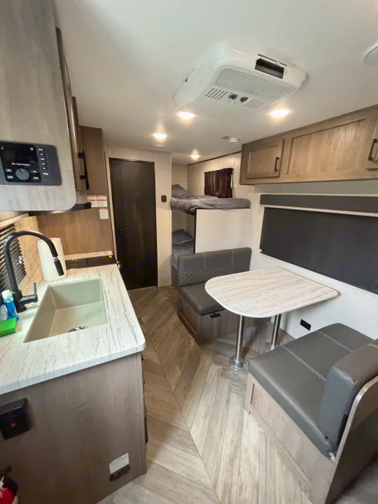 An rv rental showing its modern interior: a kitchen counter with sink, dinette, and built-in bunk beds. Designed for comfort.. Olympia Sport 19BH 2022