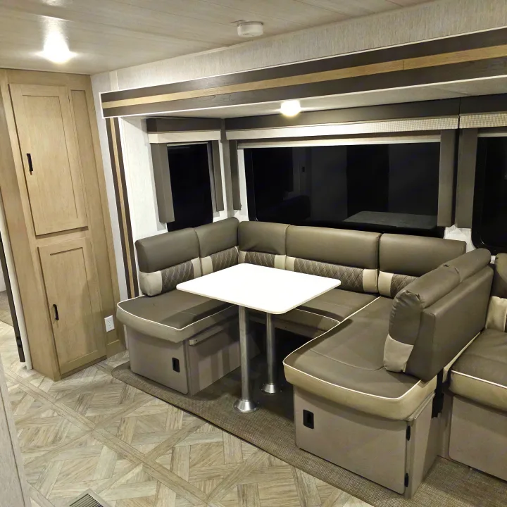 An RV rental's dinette area, featuring U-shaped gray seating, a white table, and light wood cabinetry for a cozy camper interior.. Forest River Salem Platinum 2023