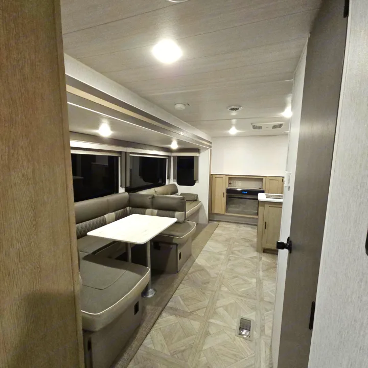 A welcoming rv rental interior with a spacious U-shaped dinette, modern kitchen area, and bright, comfortable living space.. Forest River Salem Platinum 2023