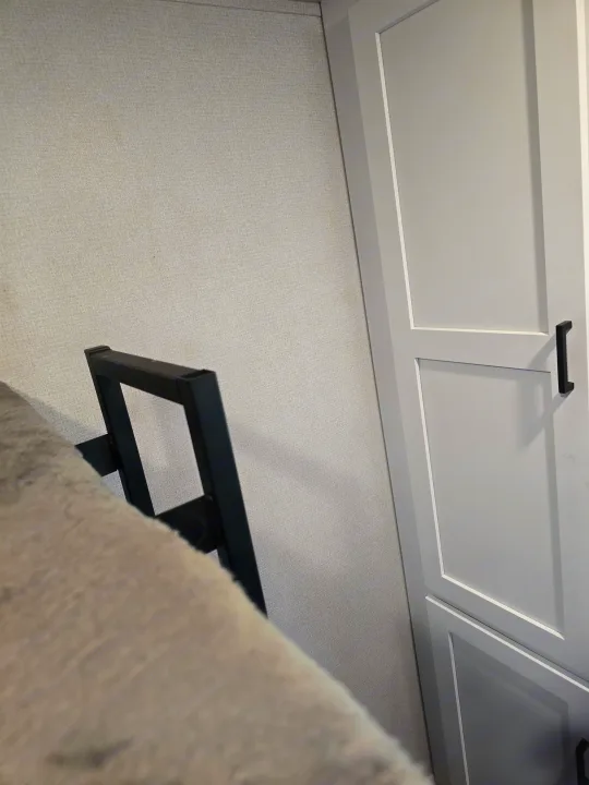 RV rental interior: white paneled cabinet with black handle, light gray textured wall, and a gray bunk with black frame.. Keystone RV Hideout 2023