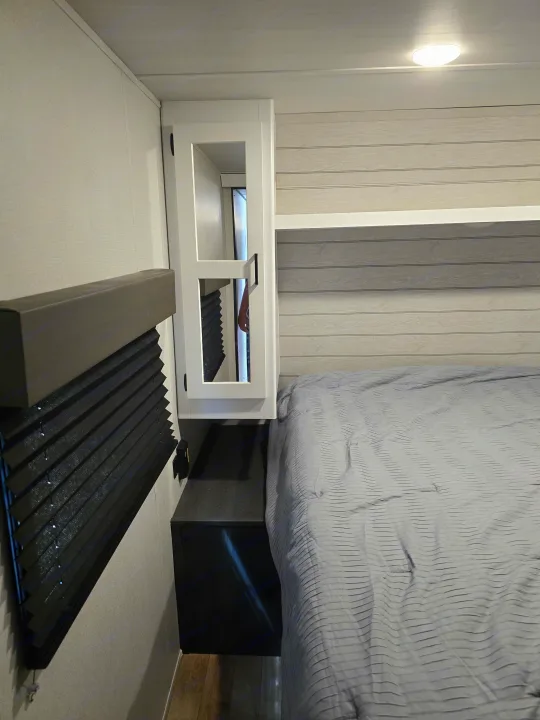 RV rental bedroom showcasing a comfortable gray bed, built-in storage cabinet, and window blinds for a cozy travel space.. Keystone RV Hideout 2023