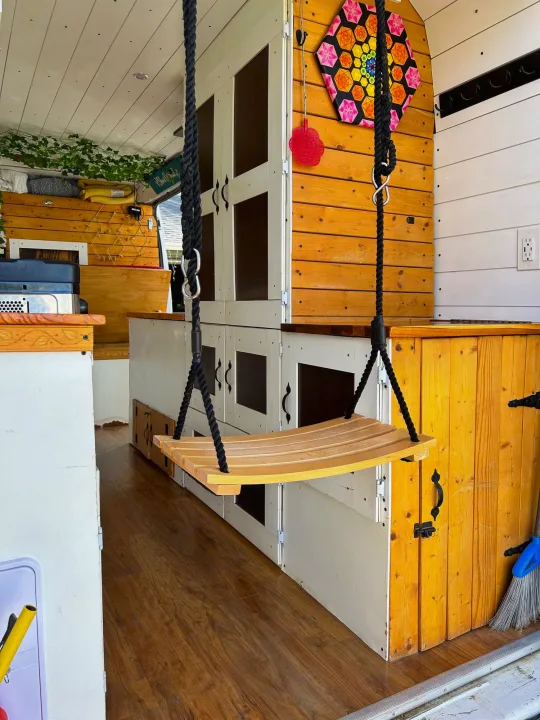 Cozy custom RV rental interior featuring a unique wooden swing, ample storage, and functional amenities for mobile living.. Ram Dodge Promaster 3500 2019