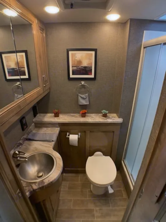 Modern RV rental bathroom with compact sink, toilet, and shower. Clean interior for comfortable travel.. Thor 33.2 2020