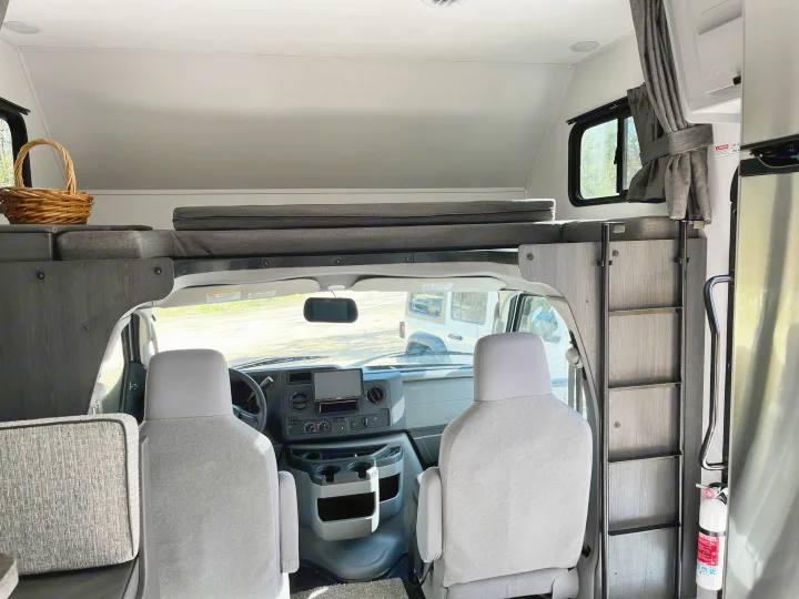 Cozy RV rental interior with over-cab bunk, driver's cabin, and essential safety features like a fire extinguisher.. Forest River Solera 27 DSE 2023