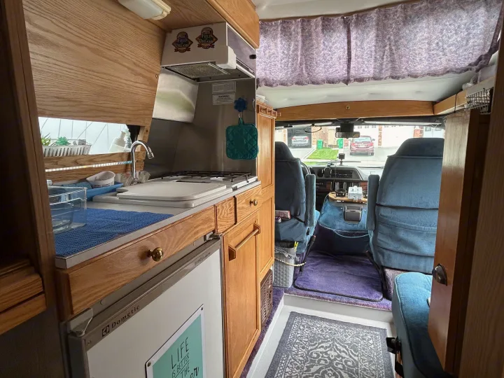 RV rental interior: cozy kitchenette with stove, sink, Dometic fridge, and comfy front cabin seating.. Roadtrek 190 Popular 1997
