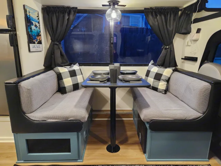 Cozy RV rental dinette features grey booth seating, full table settings, and a Lake Tahoe print.. Four Winds Majestic 2008