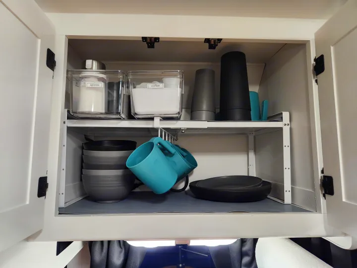 Inside an RV rental cabinet: organized kitchen essentials like spices, coffee, cups, bowls, and plates.. Four Winds Majestic 2008
