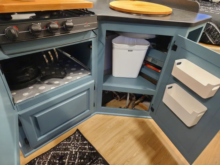 Compact RV rental kitchen's smart storage: Wedgewood Vision cooktop, organized pots, and a pull-out trash bin. Efficient design.. Four Winds Majestic 2008