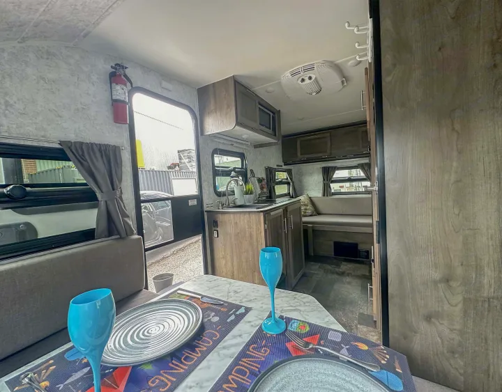 Cozy rv rental interior featuring a dining area with place settings, kitchen, and sofa. Ideal for camping adventures.. Prolite Evasion 2021