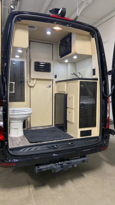Luxury RV rental van interior: a compact bathroom with toilet, full kitchenette with sink, microwave, and refrigerator.. Ultimate Toys Ultimate Coach 2024