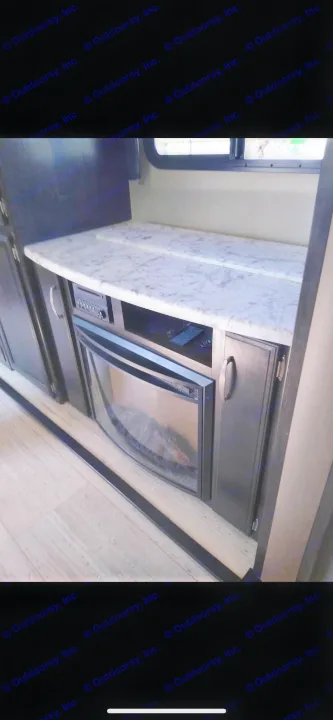 RV rental entertainment center featuring an electric fireplace, stereo, and sleek marble-look counter. Ideal for comfortable travels.. Grand Design Imagine 2018