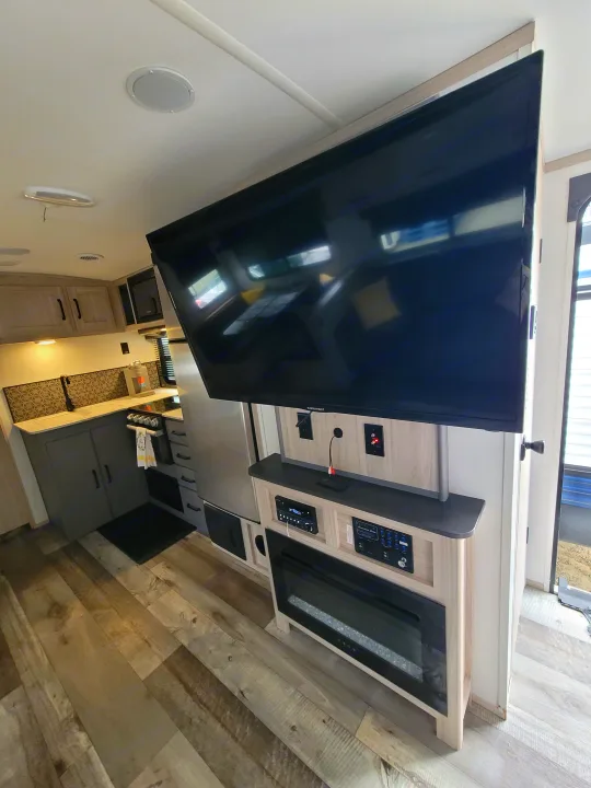 Spacious RV rental interior featuring a modern kitchen, large TV, and entertainment center with a cozy electric fireplace.. Heartland RVs Sundance Ultra Lite 2022