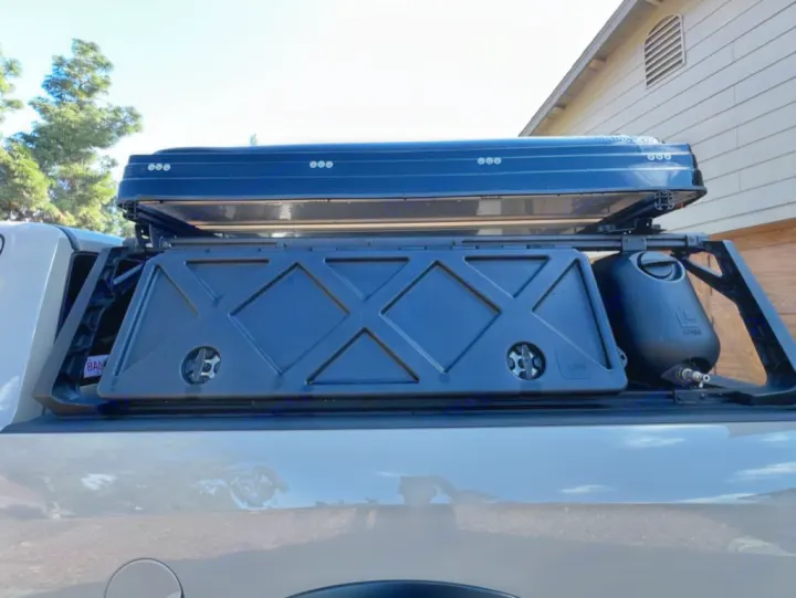 Overlanding truck bed with black rooftop tent, storage box, & water tank on a rack. Great for your next RV rental.. Dodge Dodge 1 Ton Pu 2018