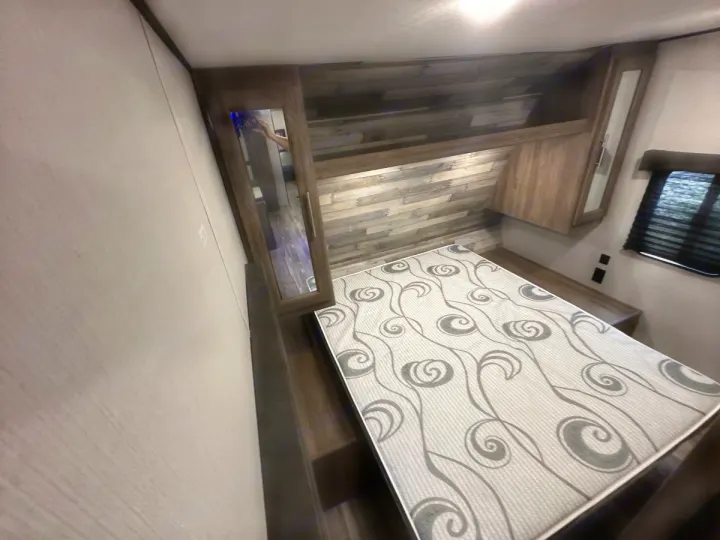 RV rental bedroom: comfortable mattress, wood-paneled headboard, mirrored cabinet, and window. Your cozy retreat.. Crossroads 328SB 2020
