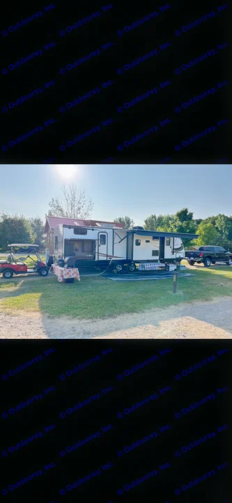Spacious RV rental parked at a sunny campsite with a truck and golf cart, perfect for outdoor adventures.. Heartland RVs Sundance XLT 2016