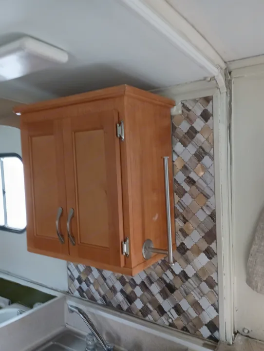 RV rental kitchen featuring light wood cabinets, a stylish arabesque tile backsplash, and a functional sink area.. Trailmanor Trailmanor Trailer 2005