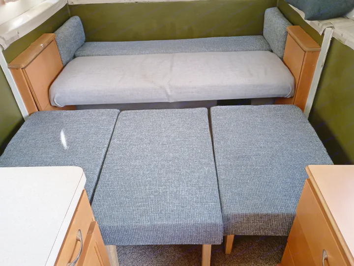 RV rental interior with a convertible sofa bed and extra floor cushions for extended sleeping.. Trailmanor Trailmanor Trailer 2005