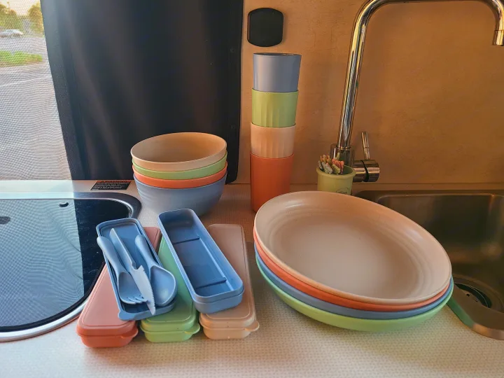 Inside an RV rental: pastel bowls, plates, cups, and cased cutlery, perfect for travel dining and camping.. Winnebago Solis 2021