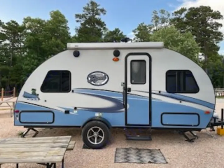 This blue and white teardrop RV rental, perfect for camping trips, is parked on gravel at a sunny campsite.. R-Pod R-Pod Trailer 2018