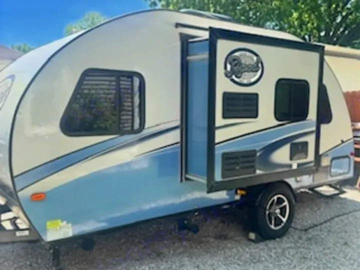This cream & blue R-Pod travel trailer, with its door open, is ready for your RV rental adventure.. R-Pod R-Pod Trailer 2018