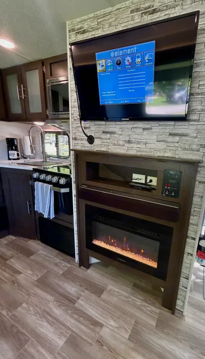 Spacious RV rental interior featuring a full kitchen, entertainment center with TV, and cozy fireplace for a comfortable stay.. Forest River Salem 2020