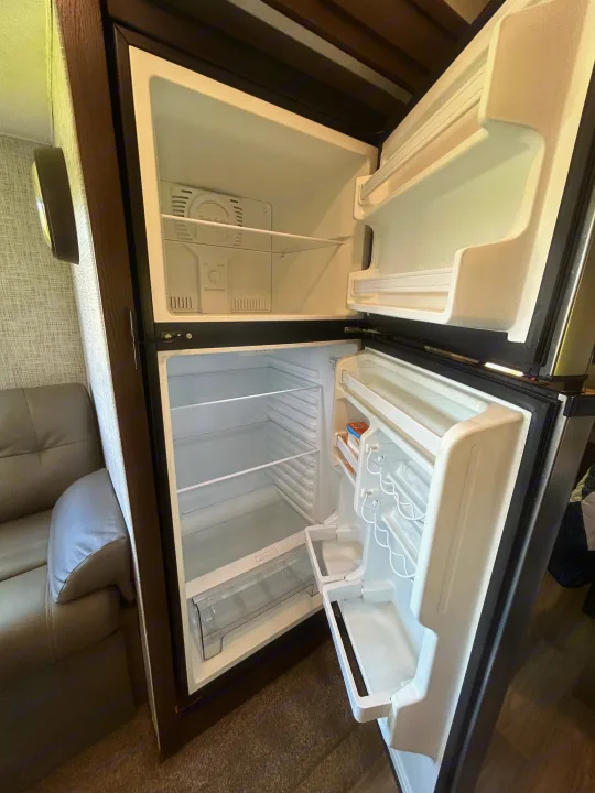 An open, clean RV rental refrigerator, featuring an empty freezer and fridge, awaiting your provisions.. Forest River Salem 2020