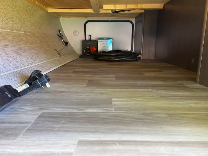 Spacious RV rental storage bay with essential camping gear: power adapter, hose, and drain support. Clean interior.. Forest River Salem 2020