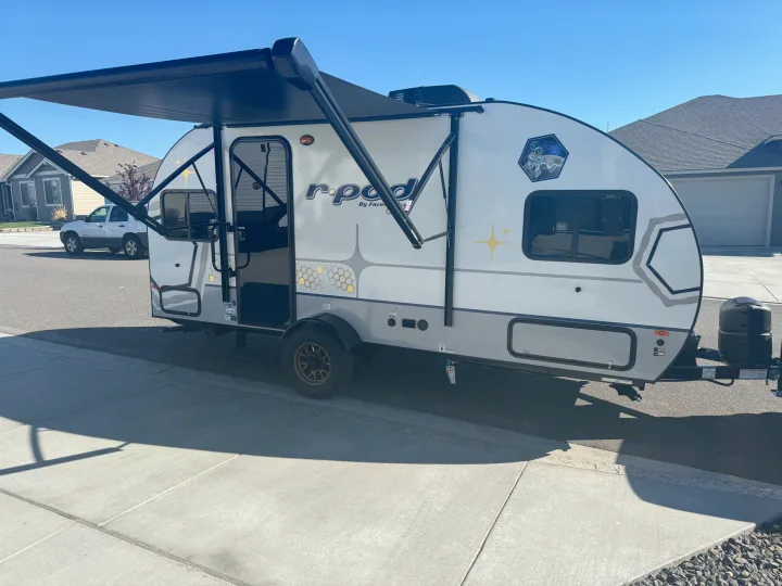 A bright R-Pod travel trailer, an ideal RV rental, showcasing its extended awning and ready for outdoor adventure.. R-Pod R-Pod Trailer 2024