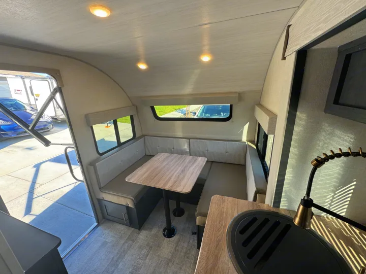 Step inside this RV rental's dinette, featuring a comfortable U-shaped bench, table, and functional kitchen space.. R-Pod R-Pod Trailer 2024