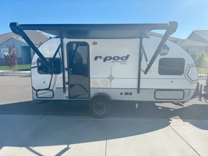 A bright white r-pod travel trailer with an extended awning, perfect for an rv rental adventure. Sunny day scene.. R-Pod R-Pod Trailer 2024