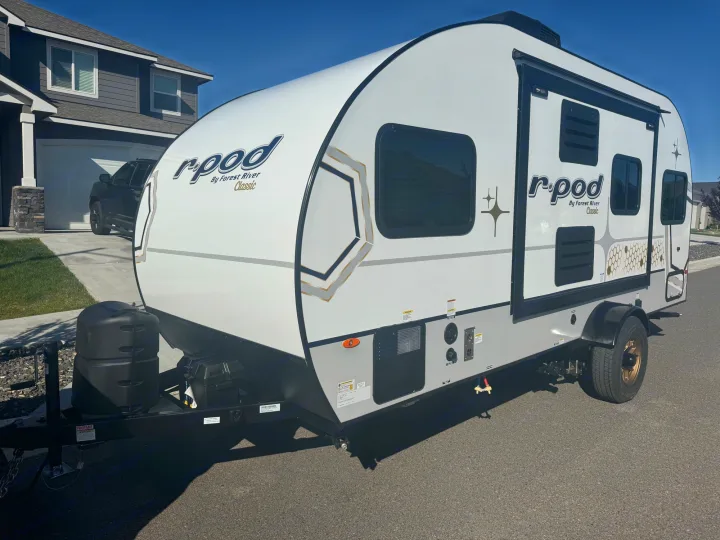 This white R-Pod travel trailer with black accents, ideal for your next RV rental adventure, is parked on asphalt.. R-Pod R-Pod Trailer 2024