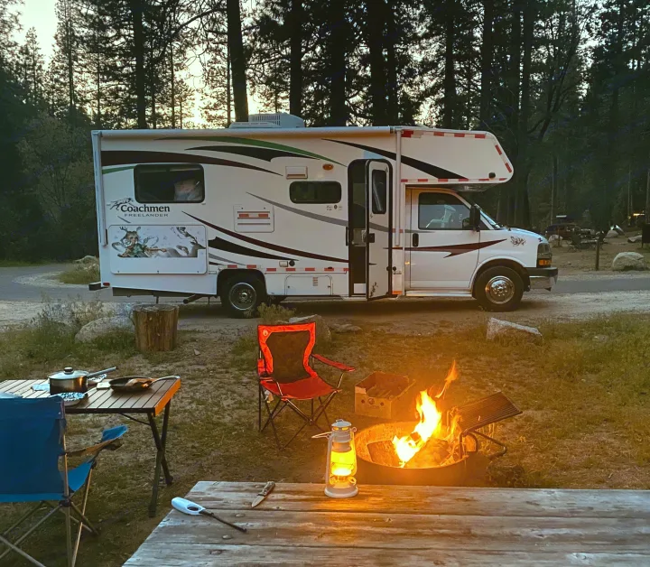 Cozy RV rental campsite at dusk. Coachmen Freelander RV, warm campfire, and outdoor cooking setup for a perfect evening.. Coachmam Freelander 21QB 2012