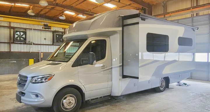 Grey Tiffin motorhome, a Mercedes-Benz Sprinter RV rental, parked indoors with expanded slide-out section.. Wayfarer Wayfarer Motorhome 2024