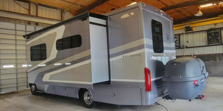 Modern grey RV with extended slide-out and rear cargo carrier, parked indoors. Ideal for your next RV rental adventure.. Wayfarer Wayfarer Motorhome 2024