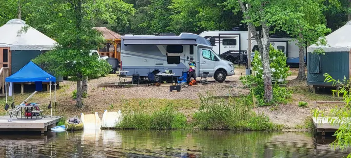 Enjoy the outdoors! RV rental parked by a lake, with yurts, kayaks & scenic camping amenities visible.. Wayfarer Wayfarer Motorhome 2024