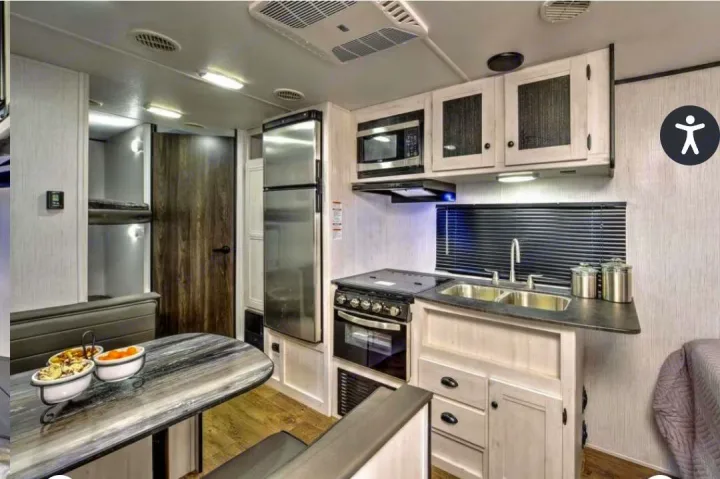 Modern RV rental interior: kitchen with sink & stove, dining booth, and bunk beds visible.. Heartland RVs Trail Runner 2022