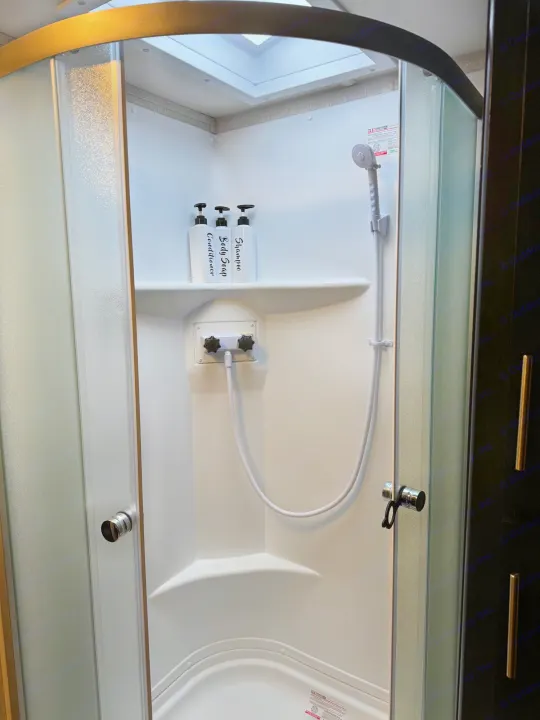 Modern RV rental shower with a skylight, shelf, and dispensers for shampoo, body soap, and conditioner. Perfect for your trip.. Greywolf 23MK 2022