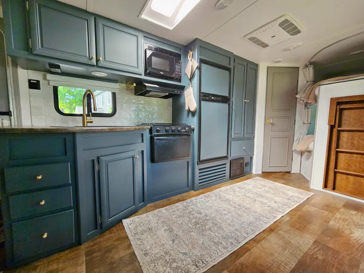 This stylish RV rental kitchen features teal cabinets, brass faucet, stove, microwave, and fridge.. Crossroads RV Z-1 2017