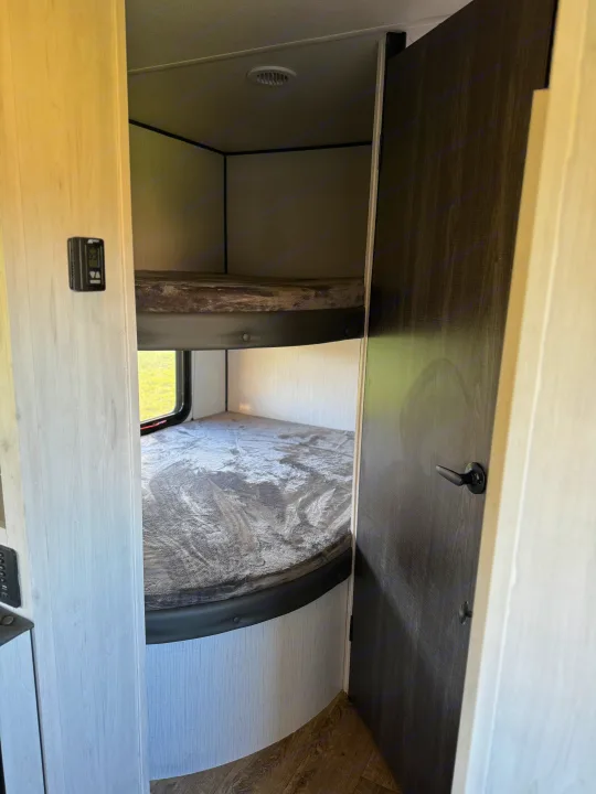 RV rental: view of cozy bunk beds. Features an upper and lower sleeping area, window, and interior door.. Heartland RVs Trail Runner 2023